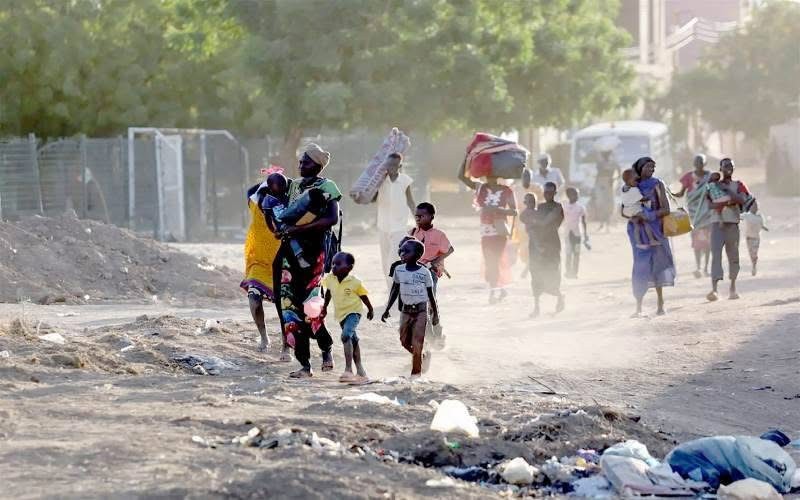 Adults and children walking along a dusty road